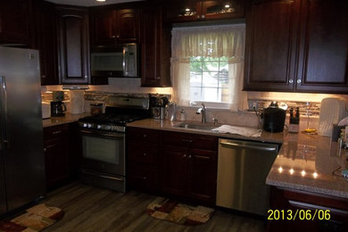 Example of a mid-sized classic u-shaped vinyl floor enclosed kitchen design in Philadelphia with a peninsula, raised-panel cabinets, dark wood cabinets, quartz countertops, multicolored backsplash, stone tile backsplash, stainless steel appliances and an undermount sink