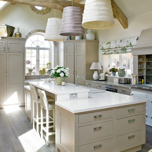 Ispirazione per una grande cucina ad U chiusa con ante lisce, ante beige, elettrodomestici in acciaio inossidabile, pavimento in legno massello medio e isola