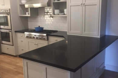 Inspiration for a mid-sized contemporary l-shaped light wood floor eat-in kitchen remodel in Salt Lake City with shaker cabinets, gray cabinets, solid surface countertops, white backsplash, subway tile backsplash, stainless steel appliances and a peninsula