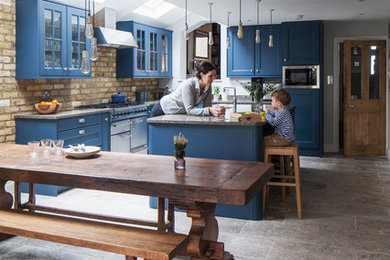 ロンドンにある中くらいなトランジショナルスタイルのおしゃれなキッチン (落し込みパネル扉のキャビネット、青いキャビネット、御影石カウンター、ベージュキッチンパネル、レンガのキッチンパネル、シルバーの調理設備、グレーの床、グレーのキッチンカウンター) の写真