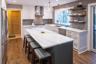 Inspiration for a mid-sized transitional u-shaped medium tone wood floor eat-in kitchen remodel in Minneapolis with an undermount sink, shaker cabinets, white cabinets, marble countertops, gray backsplash, ceramic backsplash, stainless steel appliances and an island