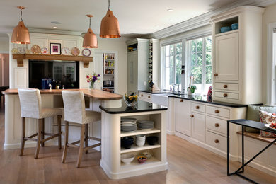 Kitchen - farmhouse l-shaped medium tone wood floor kitchen idea in Manchester with a farmhouse sink, beaded inset cabinets, white cabinets, paneled appliances and an island
