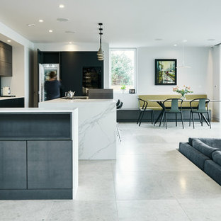 Photo of a contemporary open plan kitchen in Devon with a submerged sink, flat-panel cabinets, black cabinets, white splashback, integrated appliances, an island, white floors and white worktops.