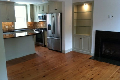 Ejemplo de cocina contemporánea pequeña abierta con armarios con paneles lisos, salpicadero beige, electrodomésticos de acero inoxidable, suelo de madera clara y una isla