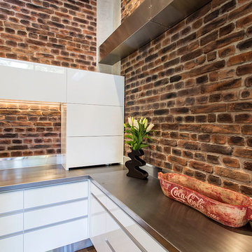 Exposed brick with stainless steel benchtops and white cabinets