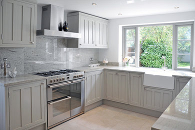 Photo of a medium sized traditional u-shaped enclosed kitchen in London with a belfast sink, shaker cabinets, grey cabinets, granite worktops, grey splashback, stone slab splashback, stainless steel appliances, ceramic flooring and no island.