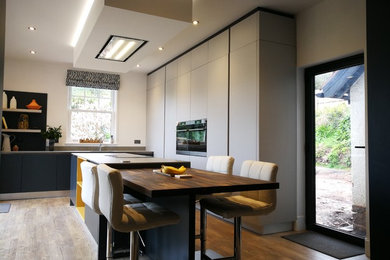 Inspiration for a large contemporary l-shaped open plan kitchen in Other with an integrated sink, flat-panel cabinets, grey cabinets, composite countertops, grey splashback, stainless steel appliances, vinyl flooring, an island, brown floors and grey worktops.
