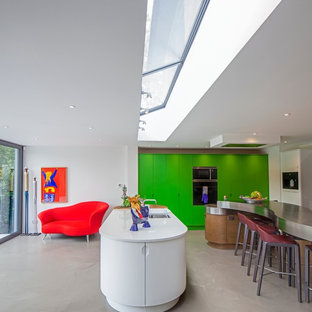 Inspiration for a contemporary u-shaped kitchen in Hertfordshire with flat-panel cabinets, green cabinets, stainless steel benchtops, panelled appliances, concrete floors, multiple islands and an undermount sink.