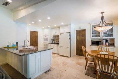 Inspiration for a mid-sized timeless galley ceramic tile and beige floor eat-in kitchen remodel in Sacramento with an undermount sink, recessed-panel cabinets, white cabinets, granite countertops, beige backsplash, brick backsplash, white appliances and a peninsula