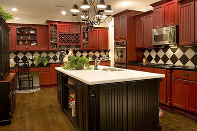 Example of a large trendy u-shaped dark wood floor and brown floor enclosed kitchen design in Cincinnati with a double-bowl sink, recessed-panel cabinets, red cabinets, granite countertops, multicolored backsplash, porcelain backsplash, stainless steel appliances and an island