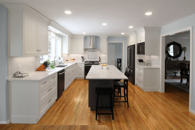 Example of a large transitional u-shaped medium tone wood floor and brown floor eat-in kitchen design in Boston with an undermount sink, shaker cabinets, white cabinets, quartz countertops, white backsplash, ceramic backsplash, black appliances, an island and white countertops