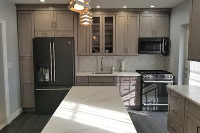 Example of a mid-sized trendy u-shaped dark wood floor and brown floor kitchen design in New York with an undermount sink, shaker cabinets, medium tone wood cabinets, marble countertops, gray backsplash, marble backsplash, stainless steel appliances and an island