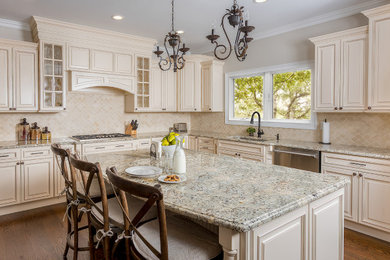 Kitchen - traditional l-shaped medium tone wood floor kitchen idea in New York with an undermount sink, raised-panel cabinets, beige cabinets, beige backsplash, stainless steel appliances, an island and multicolored countertops