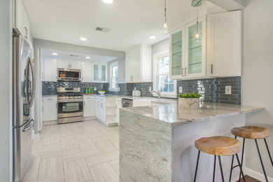 Example of a small transitional l-shaped ceramic tile and gray floor eat-in kitchen design in New York with a farmhouse sink, flat-panel cabinets, white cabinets, marble countertops, gray backsplash, porcelain backsplash, stainless steel appliances and no island