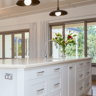 Photo of a large traditional u-shaped eat-in kitchen in Auckland with an undermount sink, recessed-panel cabinets, white cabinets, limestone benchtops, grey splashback, ceramic splashback, stainless steel appliances, laminate floors and with island.