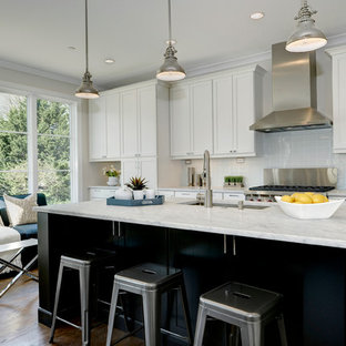 Transitional kitchen photos - Example of a transitional medium tone wood floor kitchen design in DC Metro with an undermount sink, shaker cabinets, white cabinets, gray backsplash, stainless steel appliances and an island