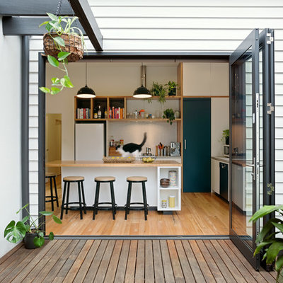 Kitchen - contemporary l-shaped medium tone wood floor and brown floor kitchen idea in Melbourne with flat-panel cabinets, white cabinets, wood countertops, white backsplash, mosaic tile backsplash, white appliances, an island and brown countertops