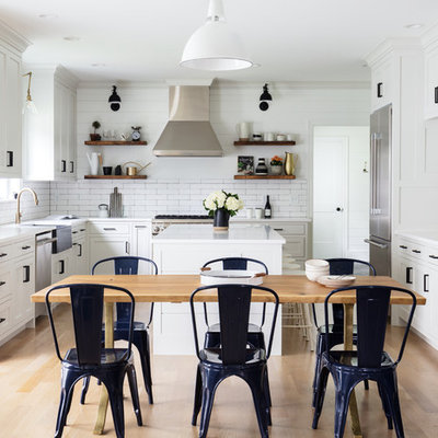 Inspiration for a huge cottage u-shaped light wood floor and brown floor eat-in kitchen remodel in New York with a farmhouse sink, white cabinets, white backsplash, ceramic backsplash, stainless steel appliances, an island, white countertops and shaker cabinets