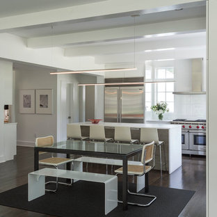Ispirazione per una grande cucina minimalista con ante lisce, ante bianche, top in superficie solida, paraspruzzi bianco, paraspruzzi in lastra di pietra, elettrodomestici in acciaio inossidabile, parquet scuro, lavello sottopiano, pavimento nero e top bianco