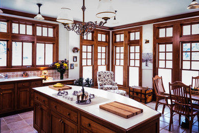 This is an example of a medium sized l-shaped kitchen/diner in New York with shaker cabinets, dark wood cabinets, ceramic flooring and an island.