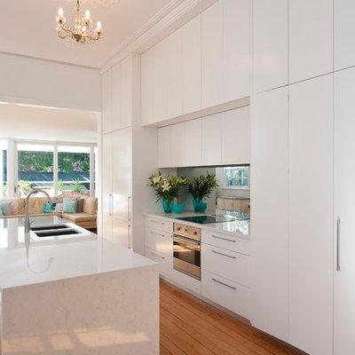 Trendy galley medium tone wood floor eat-in kitchen photo in Sydney with an island, a double-bowl sink, flat-panel cabinets, white cabinets and paneled appliances