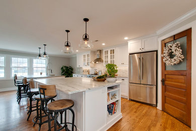 Example of a large cottage l-shaped medium tone wood floor and brown floor open concept kitchen design in Nashville with an undermount sink, shaker cabinets, white cabinets, marble countertops, white backsplash, ceramic backsplash, stainless steel appliances, two islands and gray countertops