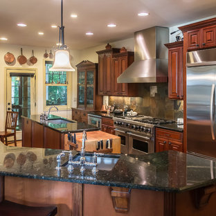 Inspiration for a large traditional u-shaped eat-in kitchen in Other with an undermount sink, raised-panel cabinets, dark wood cabinets, granite benchtops, multi-coloured splashback, slate splashback, stainless steel appliances, medium hardwood floors, multiple islands, brown floor and black benchtop.