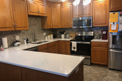 Kitchen - contemporary multicolored floor kitchen idea in St Louis with an undermount sink, raised-panel cabinets, brown cabinets, quartz countertops, gray backsplash, ceramic backsplash, stainless steel appliances and white countertops
