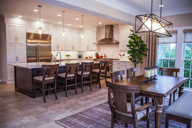 Eat-in kitchen - large modern u-shaped laminate floor eat-in kitchen idea in Other with a farmhouse sink, shaker cabinets, white cabinets, quartzite countertops, white backsplash, subway tile backsplash, stainless steel appliances, an island and white countertops