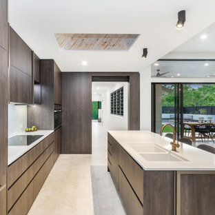 Design ideas for a large contemporary galley eat-in kitchen in Townsville with a double-bowl sink, dark wood cabinets, white splashback, ceramic floors, with island, beige floor, white benchtop, flat-panel cabinets and coloured appliances.