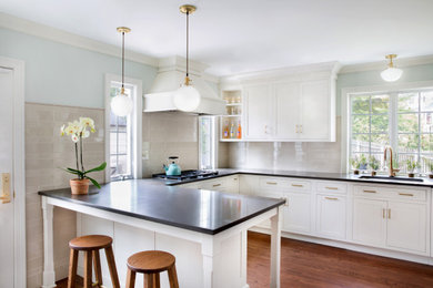 Mid-sized transitional u-shaped medium tone wood floor and brown floor enclosed kitchen photo in New York with an undermount sink, shaker cabinets, white cabinets, quartz countertops, beige backsplash, ceramic backsplash, stainless steel appliances, a peninsula and brown countertops