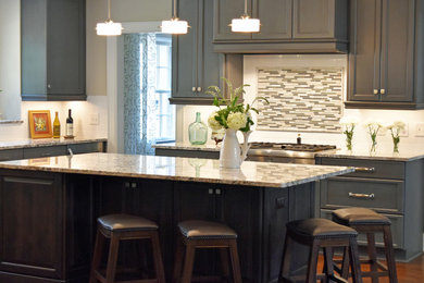 Inspiration for a large timeless medium tone wood floor eat-in kitchen remodel in Charlotte with a farmhouse sink, gray cabinets, granite countertops, white backsplash, stainless steel appliances and an island