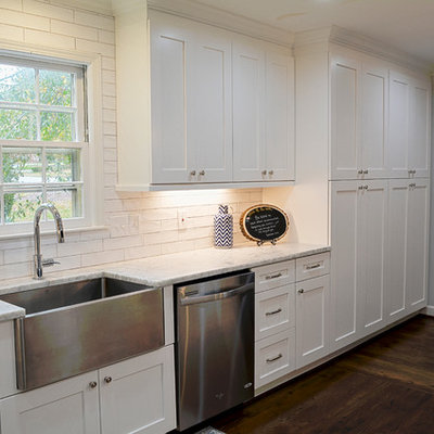 Mid-sized farmhouse l-shaped dark wood floor eat-in kitchen photo in Charlotte with a farmhouse sink, flat-panel cabinets, white cabinets, quartzite countertops, white backsplash, porcelain backsplash, stainless steel appliances and a peninsula