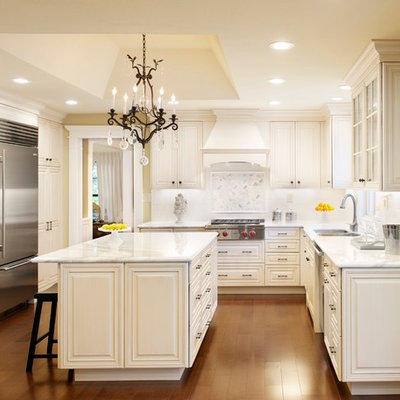 Elegant u-shaped kitchen photo in San Francisco with a double-bowl sink, raised-panel cabinets, white cabinets, white backsplash and stainless steel appliances