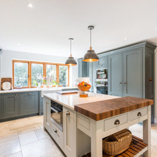 Design ideas for a large rural u-shaped kitchen in Sussex with a belfast sink, shaker cabinets, grey cabinets, quartz worktops, black appliances, an island, white worktops and beige floors.