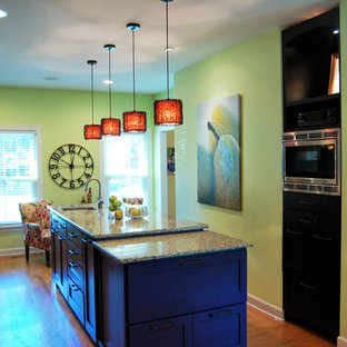 Inspiration for a large eclectic galley eat-in kitchen in Nashville with an undermount sink, shaker cabinets, blue cabinets, recycled glass benchtops, yellow splashback, glass sheet splashback, stainless steel appliances, light hardwood floors and with island.