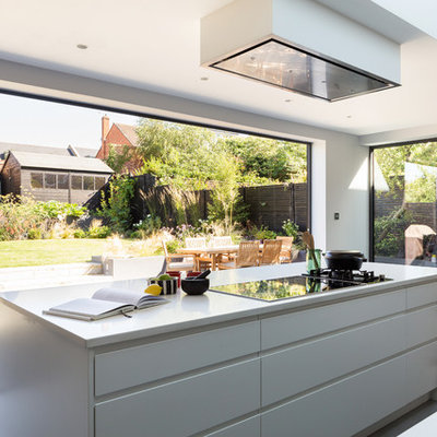 Kitchen - contemporary concrete floor kitchen idea in London with flat-panel cabinets, white cabinets and an island