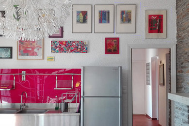 エクレクティックスタイルのおしゃれなキッチン (ピンクのキッチンパネル、ガラス板のキッチンパネル、シルバーの調理設備、ダブルシンク、ステンレスカウンター) の写真
