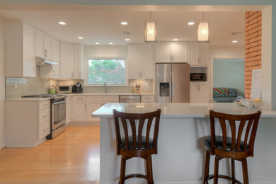 Mid-sized transitional l-shaped light wood floor and beige floor eat-in kitchen photo in Other with an undermount sink, shaker cabinets, white cabinets, quartz countertops, gray backsplash, glass tile backsplash, stainless steel appliances and a peninsula