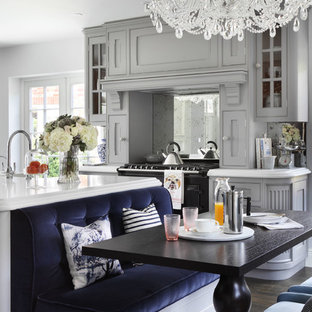 Large classic kitchen/diner in London with grey cabinets, marble worktops, metallic splashback, mirror splashback, dark hardwood flooring and an island.