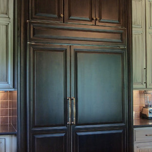 Exemple d'une grand cuisine ouverte chic en L avec un plan de travail en granite, une crédence marron, un sol en calcaire, un placard avec porte à panneau surélevé, des portes de placard en bois vieilli, un électroménager en acier inoxydable et un îlot central.