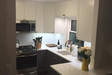 Example of a small trendy u-shaped dark wood floor and brown floor enclosed kitchen design in New York with an undermount sink, raised-panel cabinets, gray cabinets, quartz countertops, white backsplash, ceramic backsplash, stainless steel appliances, no island and white countertops