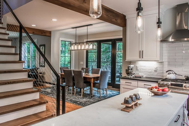 Inspiration for a mid-sized transitional l-shaped medium tone wood floor and brown floor enclosed kitchen remodel in Other with shaker cabinets, white cabinets, quartz countertops, white backsplash, stainless steel appliances, an island, a farmhouse sink, ceramic backsplash and white countertops