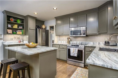 Minimalist l-shaped light wood floor and brown floor eat-in kitchen photo in Richmond with gray cabinets, quartzite countertops, beige backsplash, ceramic backsplash, stainless steel appliances, an island and an undermount sink