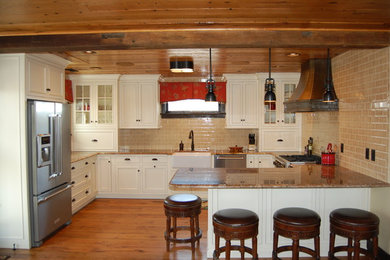 Example of a small country u-shaped medium tone wood floor eat-in kitchen design in DC Metro with a farmhouse sink, glass-front cabinets, white cabinets, granite countertops, beige backsplash, subway tile backsplash, stainless steel appliances and a peninsula