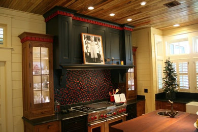 Example of a large farmhouse l-shaped medium tone wood floor eat-in kitchen design in Atlanta with a farmhouse sink, beaded inset cabinets, black cabinets, granite countertops, multicolored backsplash, glass tile backsplash, stainless steel appliances and an island