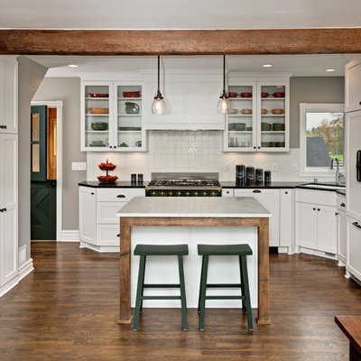 Inspiration for a mid-sized country l-shaped dark wood floor open concept kitchen remodel in Minneapolis with an undermount sink, shaker cabinets, white cabinets, white backsplash, an island, soapstone countertops, ceramic backsplash and paneled appliances