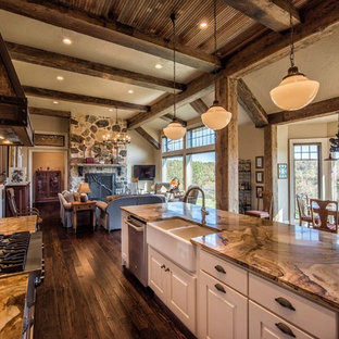 Photo of a mid-sized country galley open plan kitchen in Other with a farmhouse sink, raised-panel cabinets, white cabinets, onyx benchtops, stainless steel appliances, medium hardwood floors and with island.