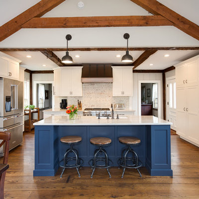 Example of a large country medium tone wood floor and brown floor eat-in kitchen design in Providence with white cabinets, quartzite countertops, white backsplash, brick backsplash, stainless steel appliances, an island and shaker cabinets