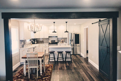 Inspiration for a mid-sized cottage l-shaped vinyl floor eat-in kitchen remodel in Other with a farmhouse sink, shaker cabinets, white cabinets, quartz countertops, gray backsplash, subway tile backsplash, stainless steel appliances, an island and white countertops